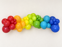 Rainbow grab-and-go balloon garland on a clean white wall
